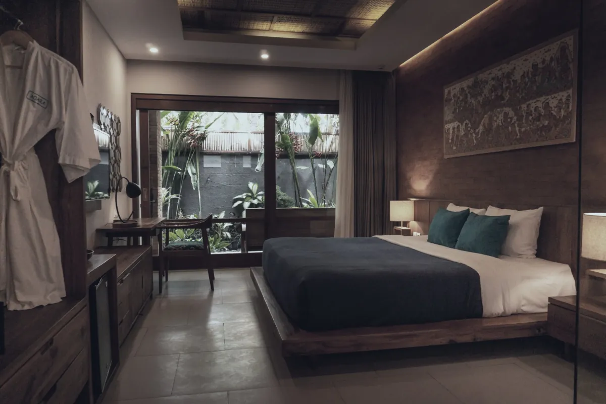 A lodge room made up: bed turned down, warm light, garden outside.